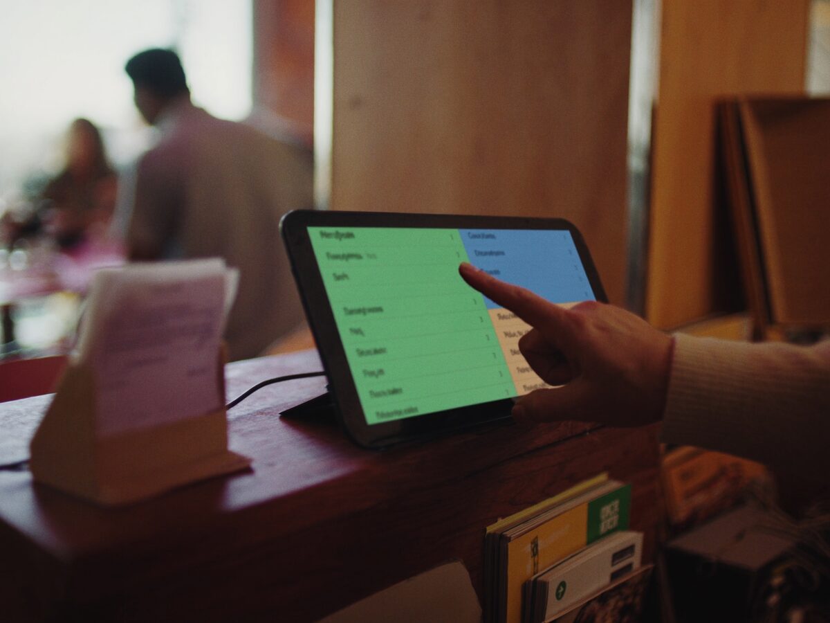 Hand charging an order on the point-of-sale touchscreen at a restaurant counter